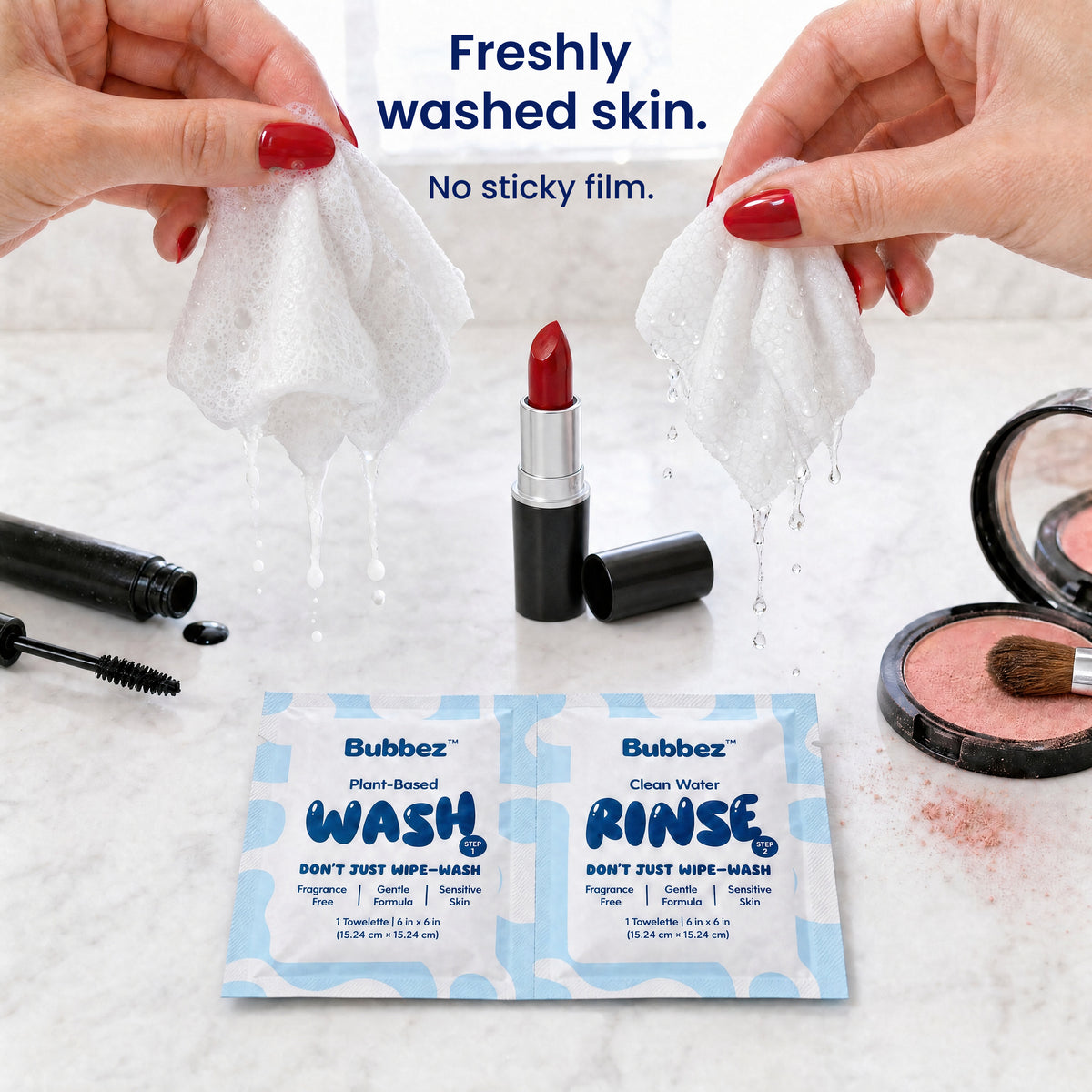 Two hands hold a lathering Bubbez WASH wipe and a dripping RINSE wipe above a marble vanity set with lipstick, mascara and blush. A WASH and RINSE twin sachet lies below. Headline reads Freshly washed skin. Not wiped.