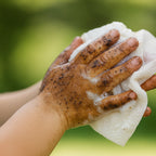 Hand with dirt being cleaned by a bubbez soap wipe against a green background