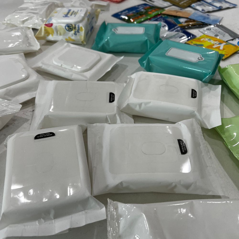 Assorted packages of wipes including white, teal, and other colors on a flat surface.