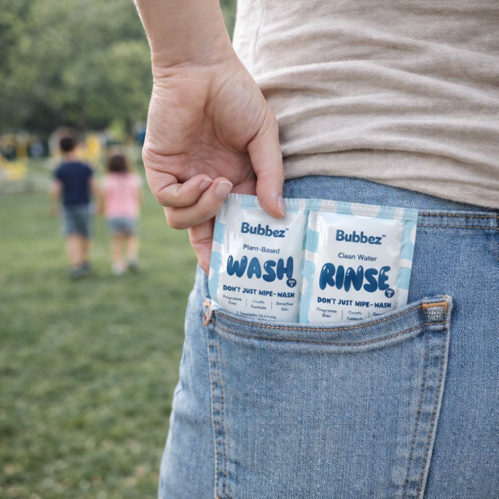 Person holding two Bubbez wash and rinse sachets in a pocket with a park background