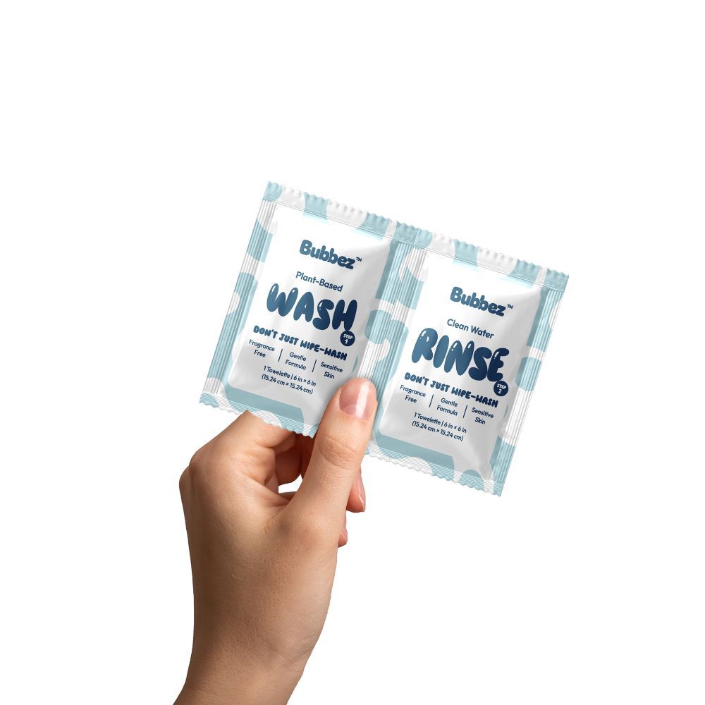 Hand holding two Bubbez cleaning product packets labeled 'Wash' and 'Rinse' on a white background.